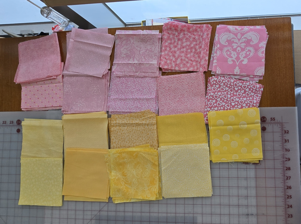 Pink and yellow fabric scraps selected for the scrappy Exploding Heart quilt.